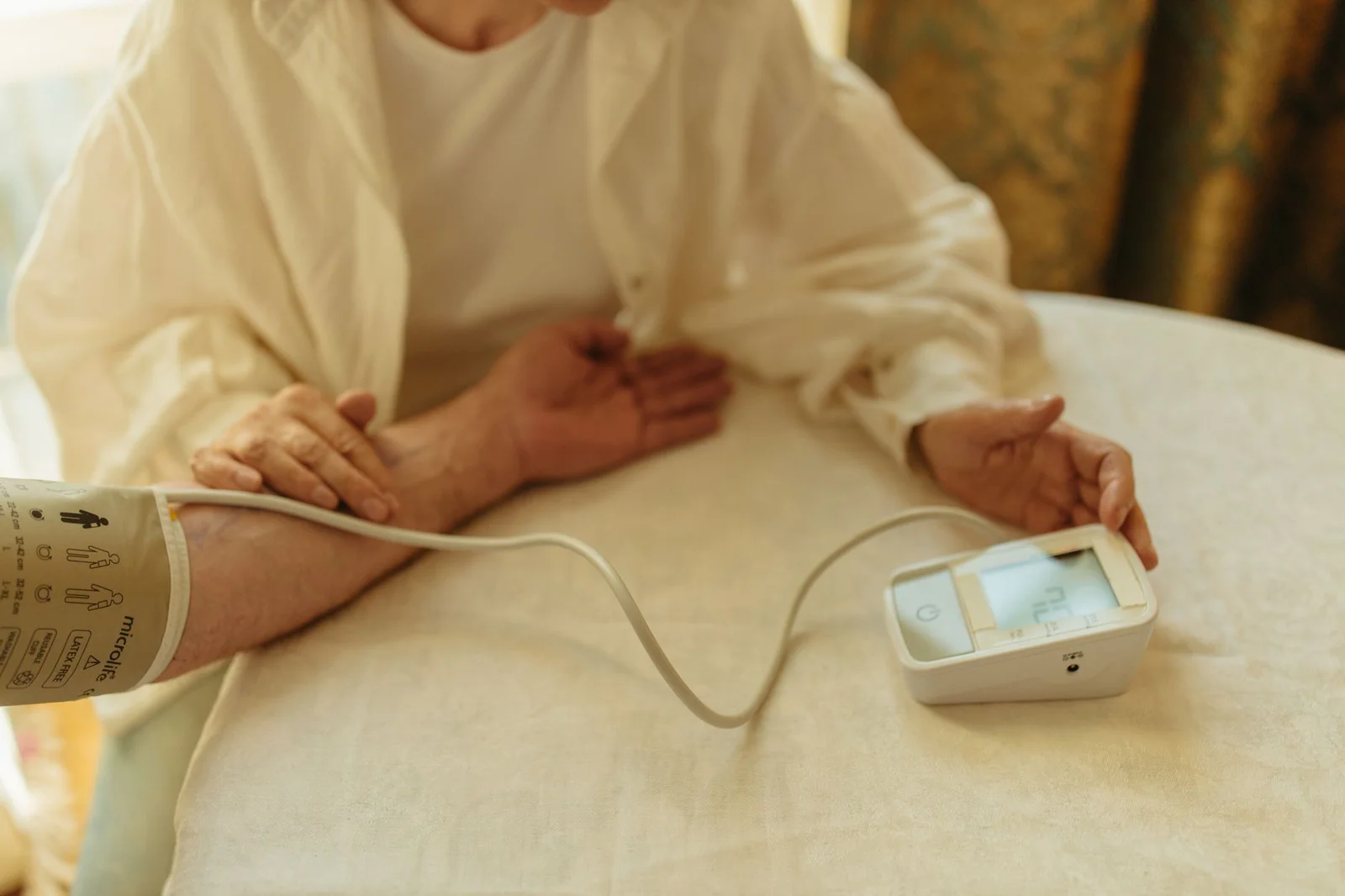 Pessoa idosa medindo a pressão arterial em casa com aparelho digital. Foto de Yaroslav Shuraev via Pexels.