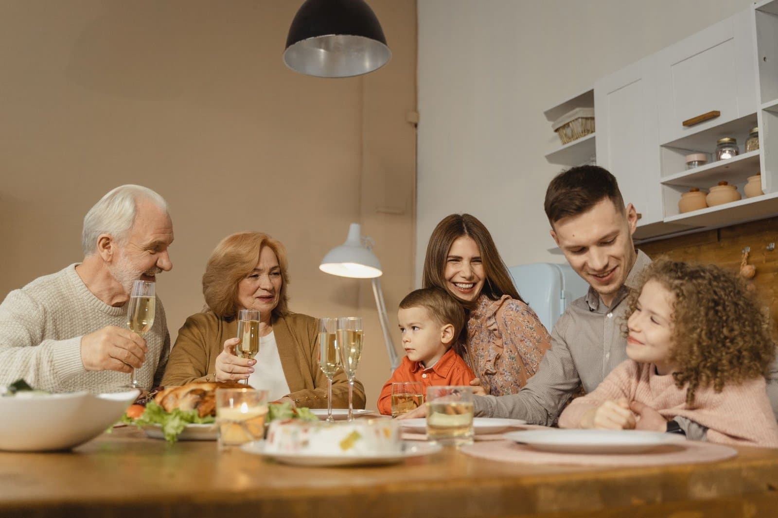 Pai idoso à mesa com a família em um almoço, ilustrando os sinais de perda auditiva em idosos. Foto de Tima Miroshnichenko via Pexels.