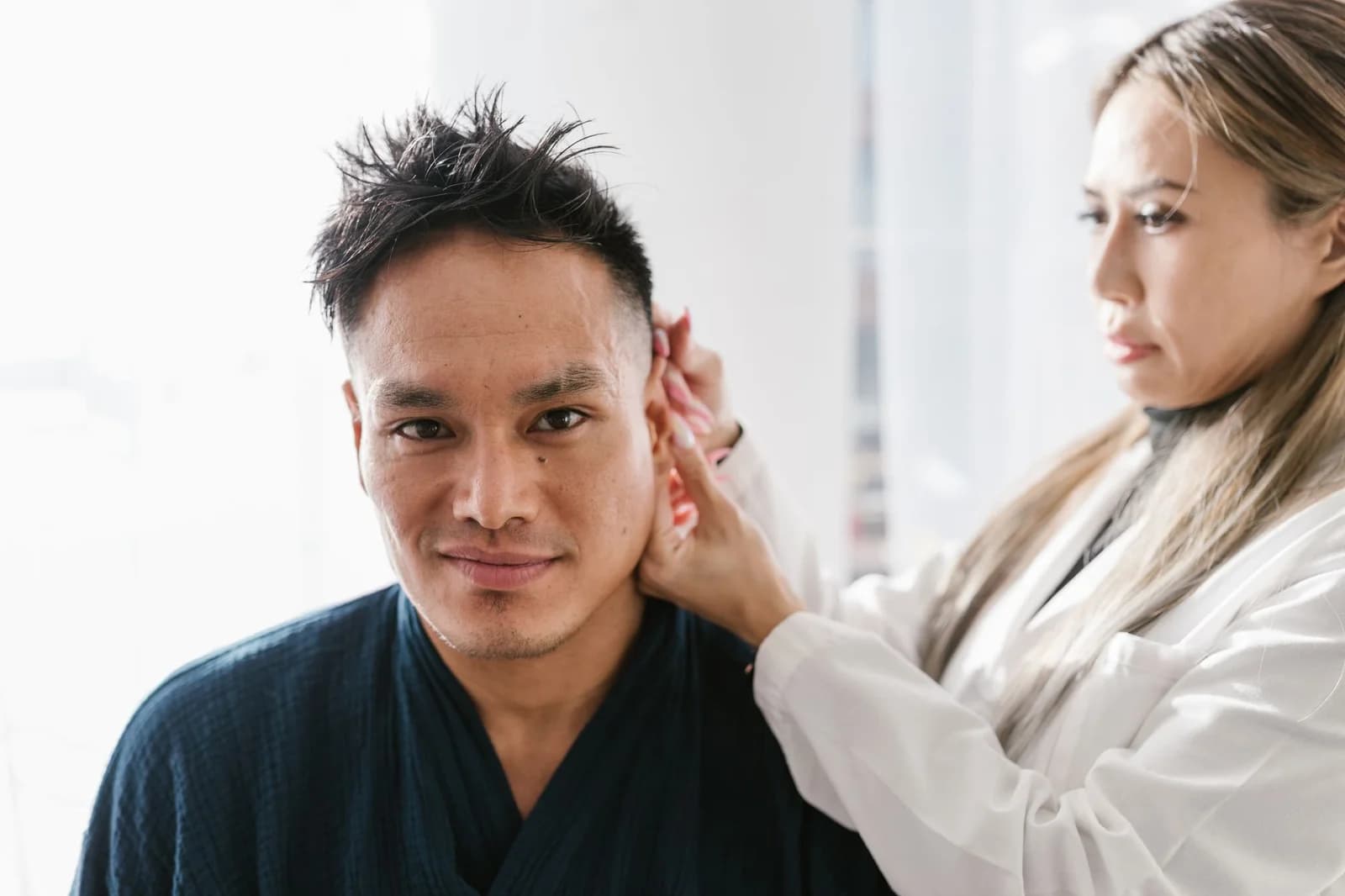 Fonoaudióloga examinando o ouvido de um paciente em consultório. Foto de RDNE Stock project via Pexels.