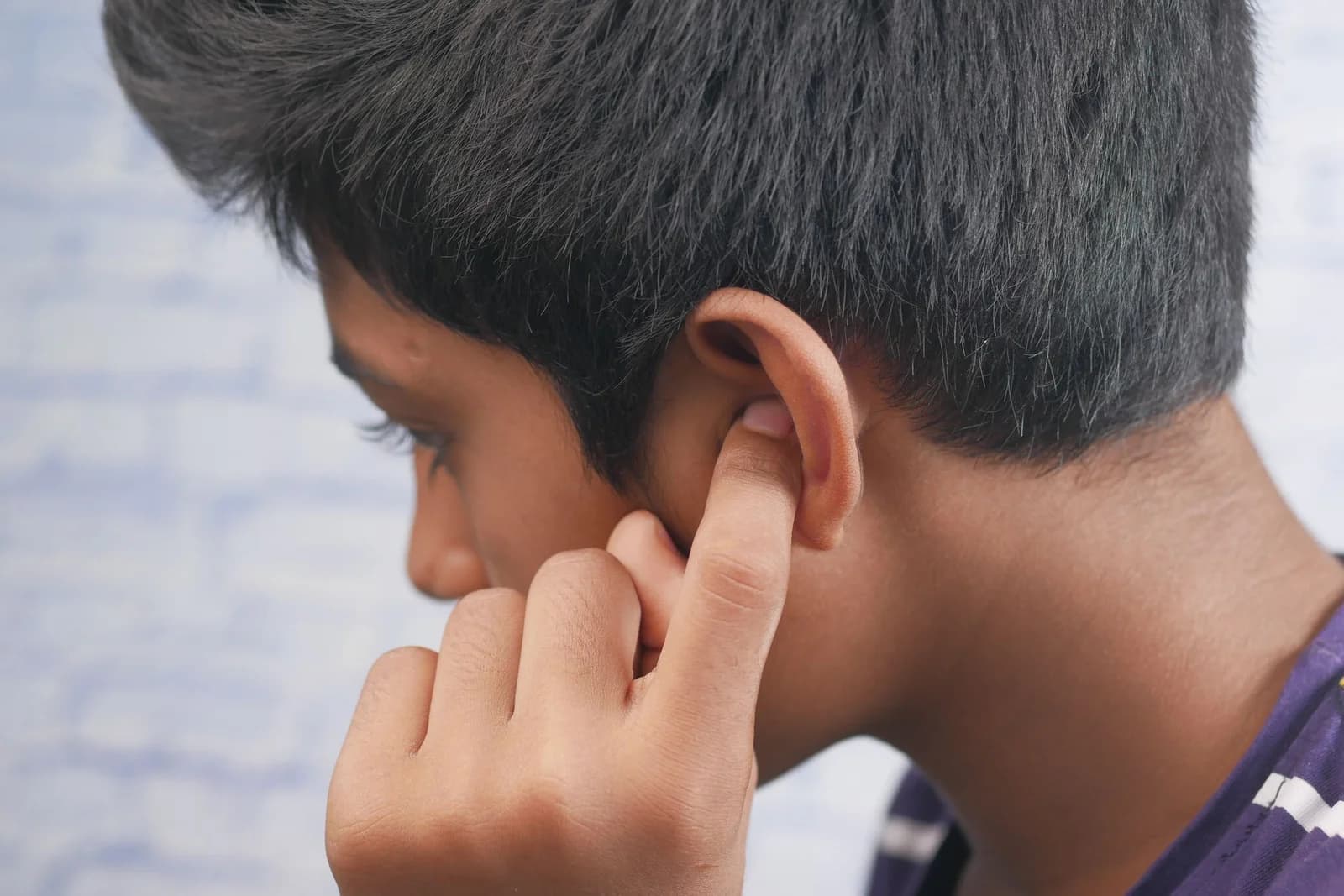 Pessoa com a mão sobre a orelha, sugerindo ardência e desconforto na região. Foto de Towfiqu barbhuiya via Pexels.