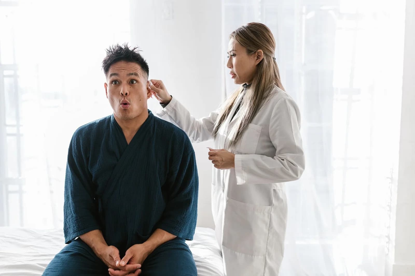 Profissional de saúde examinando o ouvido de um paciente com otoscópio em consultório. Foto de RDNE Stock project via Pexels.