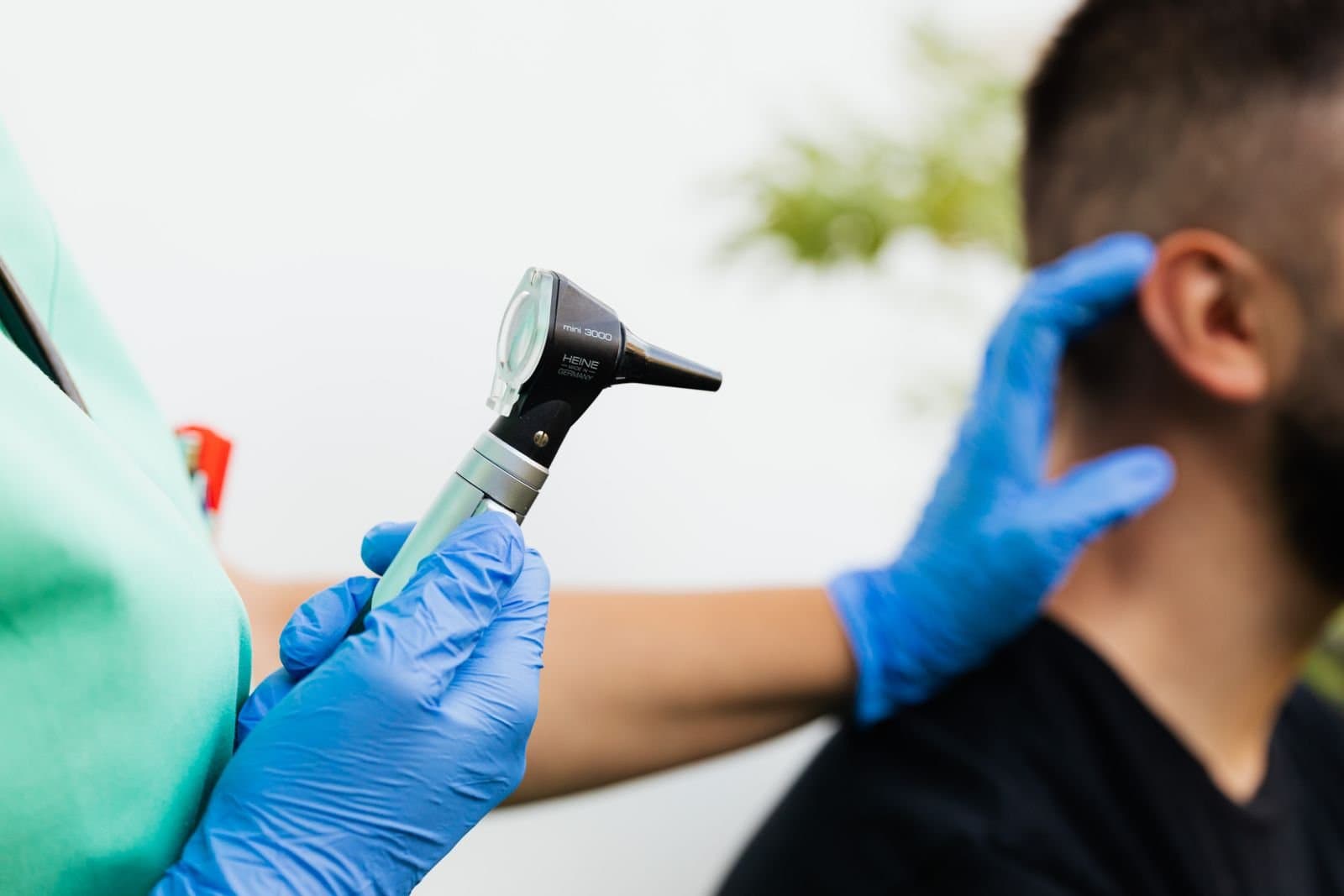 Profissional de saúde examinando o ouvido de um paciente com otoscópio em consultório. Foto de Kaboompics via Pexels.