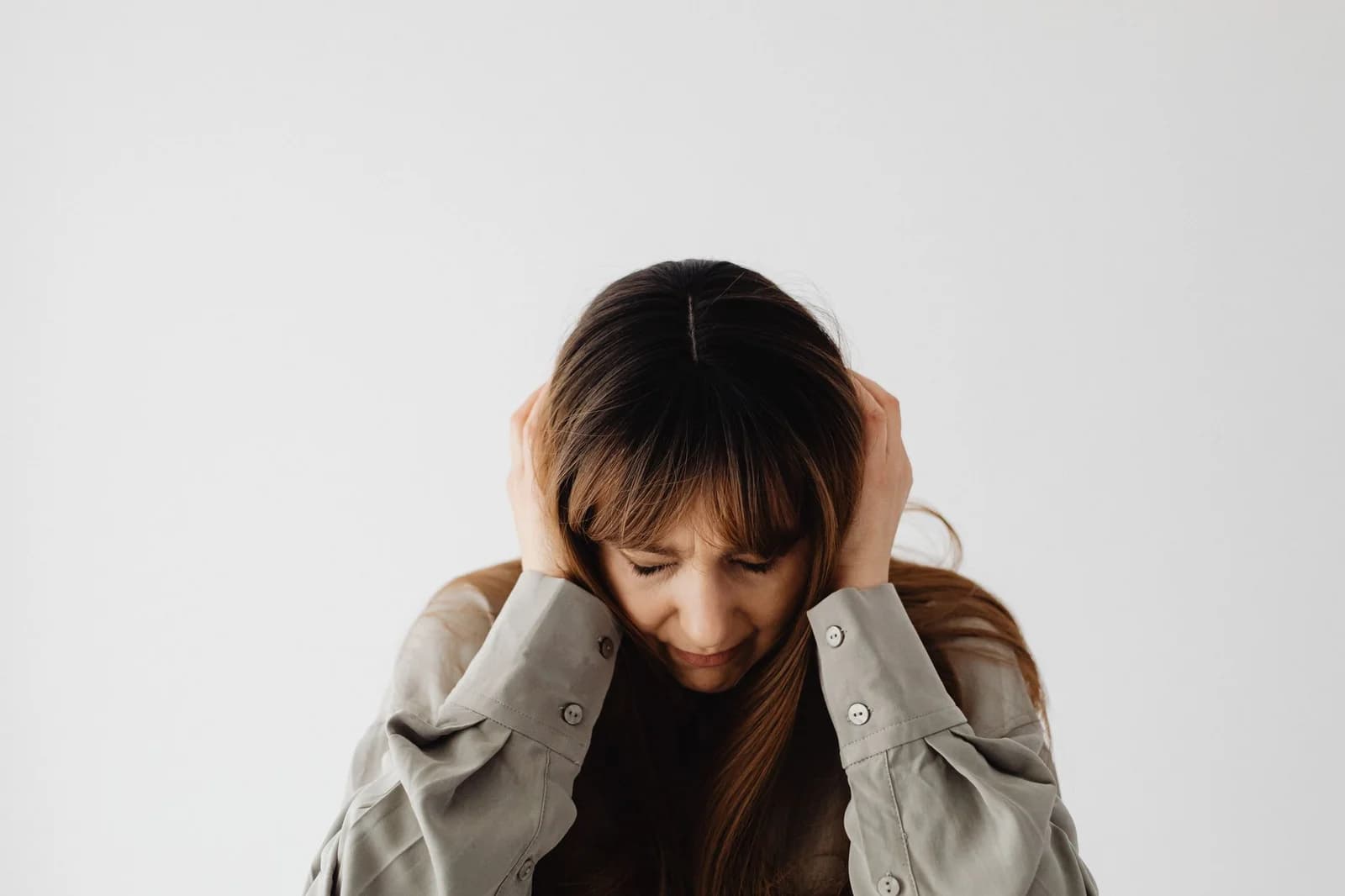 Mulher levando a mão ao ouvido, ilustrando a percepção de zumbido. Foto de Kaboompics via Pexels.